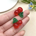 Close-up of two red acrylic cherry charms with green leaves for DIY jewelry making - Red Cherry (22162)