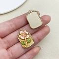 Macro shot of gold enamel flower pendant with pink petals and green leaves detail - Yellow Square Monet Garden Peach Flower Leaf (22114)