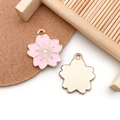Macro shot of pink cherry blossom pendants with golden metal texture and petal details - Pink Enamel Cherry Blossom Style (14791)