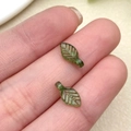Macro detail of translucent green acrylic leaf beads with delicate carved vein textures - Dark Green Mini Leaf (22136)