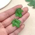 Detail of green acrylic leaf pendants held in hand showing size for DIY jewelry making - Maple Leaf (22149)