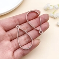 Marcos metálicos plateados en forma de gota para joyería DIY, mostrados en mano - Marco de Gota de Agua (22379)