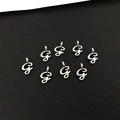 Makroaufnahme von acht silbernen Legierungs-Anhängern mit dem Buchstaben G für DIY - Buchstabe G