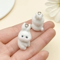 Detail showing two cute white flocked rabbit charms with metal rings held in a hand - Rabbit Style