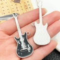 Detailopname van punk gitaarhangers in de hand met zwart emaille en metalen rooster - Zwart Emaille Symbool Gitaar (22355)