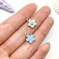 Macro detail of two small floral charms on a finger with silver finish and blue enamel - Lake Blue Flower Style (21926)