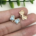 Blue enamel bow pendant with gold trim for DIY jewelry making shown on fingertips - Lake Blue Bow