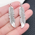 Dettaglio di due ciondoli a piuma d'argento con trama metallica e anello di aggancio - 10x45mm / Ciondolo Foglia Piuma Argento Antico (B296)