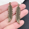 Detail of bronze feather alloy pendants with intricate vein patterns for DIY jewelry making - 12x46mm / Antique Bronze Feather Leaf Pendant (1069)