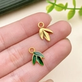 Detail view of bamboo leaf pendant in matte gold finish with green enamel accent - Bright Gold Bamboo Leaf Charm (22827)