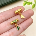 Detailed close-up of matte gold bamboo pendants with green enamel leaves held by a hand - Matte Gold Bamboo Leaf Joint Charm (22829)