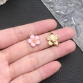 Pink enamel and gold-plated floral pendants held for scale on leather background - Pink Enamel Cherry Blossom (10961)