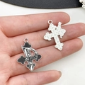 Gothic cross pendants with grim reaper design and textured silver finish, shown in hand - Reaper Scythe Cross Style (19385)