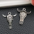 Detail view of antique silver bull skull charms showing floral engraving and hollow back - Realistic Bull Head Style (18708)