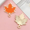 Detail of maple leaf metal pendant with orange enamel finish and textured gold back - Orange Enamel Maple Leaf (15496)
