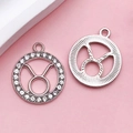 Silver Taurus zodiac pendant set with sparkling rhinestones on a pink background - Taurus