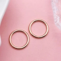 Close-up of two polished rose gold minimalist round rings on a soft pink surface - Circle Link