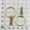 Detailed view of 25mm gold-plated keychain rings with chain on a metric scale grid - KC Gold 25mm Ring With Chain (13505)