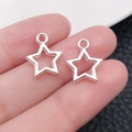 Gros plan de breloques étoiles évidées en argent portées à la main pour bijoux DIY - Pendentif Étoile Ajourée Argent Brillant (20848)