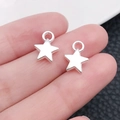 Pendentif étoile en alliage argenté montré sur le doigt pour la taille des bijoux DIY - Pendentif Petit Pentagramme Argent Brillant (20846)