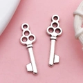 Set of two vintage silver alloy key charms for DIY jewelry making on pink background - Key (17324)