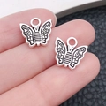 Vue macro d'un pendentif papillon en argent antique tenu à la main pour l'échelle - Style de Papillon (17318)