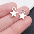Pair of small silver star alloy charms for DIY necklaces held on a fingertip - Solid Star Style(3)