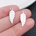 Detailed view of silver antique leaf charms for DIY jewelry making held by hand - Bright Silver Leaf (19903)