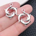 Macro shot of two vintage silver dolphin circle pendants held in hand over black leather - Marine Three Dolphins (16306)