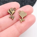 Close-up of vintage bronze flower charms held by hand to show fine detail and small size - Rose (20495)