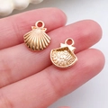 Golden seashell charm pendant for DIY jewelry making shown held between fingers - Small Shell Pendant (11599)