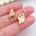 Pendentif coquillage doré pour création de bijoux DIY, montré en main pour taille - Pendentif Conque (18305)