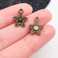 Antique bronze alloy flower charm for jewelry making shown held by fingertips - Small Flower (20482)
