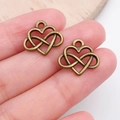 Close-up of antique bronze heart and infinity charms held in hand for DIY jewelry making - Infinity Symbol Heart Charm (19941)