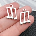Silver musical note pendants for DIY jewelry making shown in hand for size context - Antique Silver Triple Notes (9162)