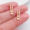 Miniature gold metal clothes peg pendants for jewelry making held in hand for size - Tool Clip (20253)