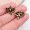 Antique bronze hollow heart charms with scrollwork patterns shown on finger for size scale - Filigree Hollow Heart Charm (19943)