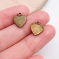 Antique bronze heart pendants for DIY jewelry making shown on fingertips for size - Matte Texture Heart Charm (19945)