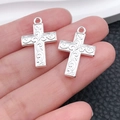 Macro shot of bright silver cross pendants with vintage embossed floral patterns for DIY - Scroll Embossed Cross Style (20364)