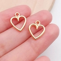 Golden heart charm pendants for DIY jewelry making shown in hand for scale - Hollow Heart Shape (15804)