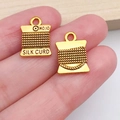 Macro shot of two vintage gold sewing machine spools charms held in hand for scale - Vintage Thread Spool (20234)