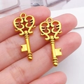 Close-up of heart-shaped gold key pendants with intricate filigree metalwork detail - Antique Gold Key (10230)
