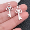 Close-up of silver heart-shaped wing key charms held in hand for jewelry making - Bright Silver Vintage Hollow Key (20964)