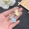 Hand holding a light blue enamel violin pendant with floral details and gold backing - Enamel Blue Cello Style / 35x24mm / Blue