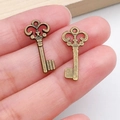 Pair of vintage bronze key charms with ornate patterns for DIY jewelry making on fingertip - Exquisite Hollow Small Key (540) / Antique Bronze