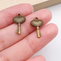 Vintage bronze heart key charms held by hand for DIY jewelry making material - Beaded Edge Heart Key (20981) / Antique Bronze