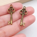 Pair of vintage bronze key charms for DIY jewelry held on finger to show compact size - Vintage Minimalist Shape Key (20982) / Antique Bronze