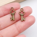 Vintage bronze alloy key charms for DIY jewelry making shown in hand for scale - Clover Hollow Key Style (20983) / Antique Bronze