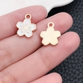 Macro shot of white and gold cherry blossom charms held on fingers for size detail - White Enamel Small Cherry Blossom (19184)