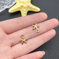 Paire de breloques étoile de mer dorées pour bijoux DIY présentées sur une paume - Pendentif Petite Étoile de Mer Océan (11594)